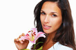 Brunette holding stargazer lily looking into camera Brunette holding stargazer lily looking into camera