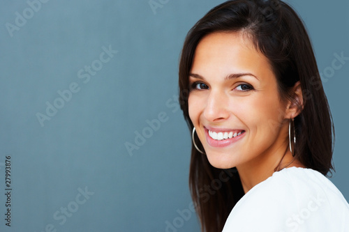 Photo: Pretty woman smiling at camera against blue background Pretty woman smiling at camera against blue background