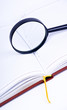 Book with magnifying glass on white background