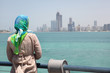 Girl in blue kerchief standing on the ship and watches Abu Dhabi