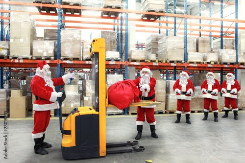 Photo: santa clauses in the line for the sacks of gifts in storehouse santa clauses in the line for the sacks of gifts in storehouse