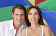Man & Woman Couple Under Multi Colored Umbrella on Beach