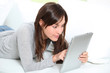 Young woman sitting on sofa with electronic pad