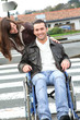 Woman helping friend in wheelchair cross the street