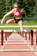 Photo: Athlete Jumping Over Hurdles on a Track Athlete Jumping Over Hurdles on a Track