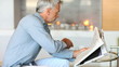 Mature man reading newspaper while drinking coffee