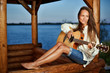 Young woman playing guitar in summerhouse on sunset