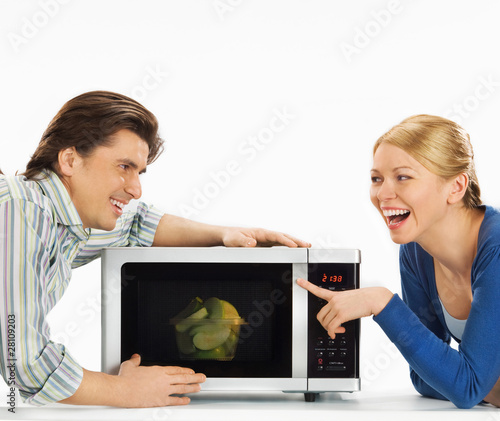 Photo: Smiling young couple preparing food in the kitchen Smiling young couple preparing food in the kitchen