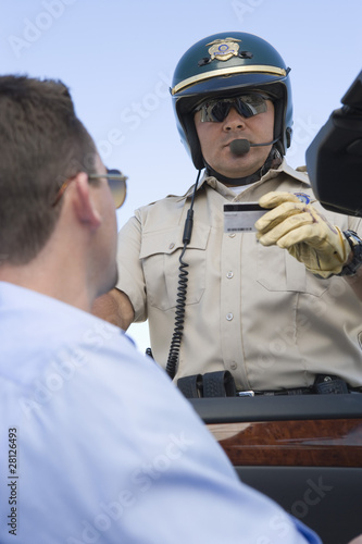 Photo: Highway patrol officer examines man's driving license Highway patrol officer examines man's driving license