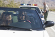 Young woman drive convertible, police officer stands at his car