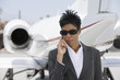 Photo: Mid-adult African-American businesswoman standing in front of private plane and talking on phone. Mid-adult African-American businesswoman standing in front of private plane and talking on phone.