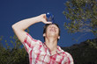 Teenage boy 16-17 years outdoors, spilling water from bottle on face, smiling
