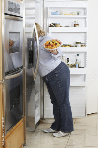 Photo: Woman looking into fridge, side view Woman looking into fridge, side view