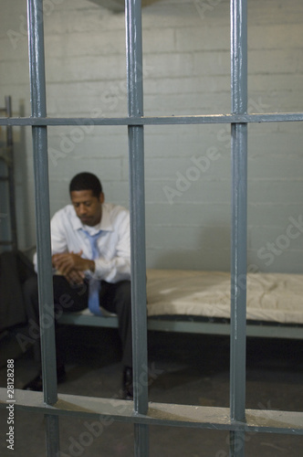 Foto: Man sitting in prison cell Man sitting in prison cell