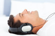 Joyful man listening music lying on his bed