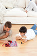 Father and son playing checkers together lying on the floor Father and son playing checkers together lying on the floor