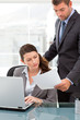 Handsome manager showing a paper to a woman at her desk