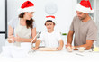 Proud parents looking at their son using a rolling pin