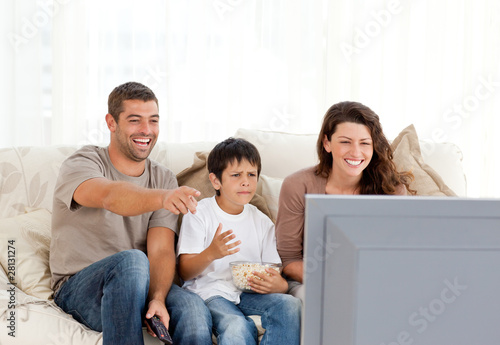 Photo: Family laughing while watching television together Family laughing while watching television together