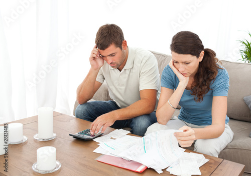 Photo: Desperate couple doing their accounts sitting on the sofa Desperate couple doing their accounts sitting on the sofa