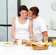 Passionate man kissing his girlfriend while cutting bread for br