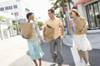 Three mid-adult friends on street holding groceries