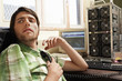 Man sitting at desk with computer equipment, holding phone.