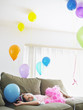 Foto: Young girl 7-9 lying on sofa looking at balloons Young girl 7-9 lying on sofa looking at balloons