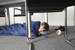 Man sleeping on floor under desk in boardroom