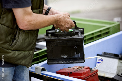 A senior man recycling a car battery.