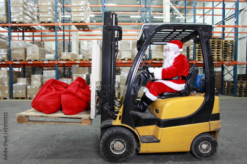 Photo: Santa Claus as a forklift operator at work in warehouse Santa Claus as a forklift operator at work in warehouse