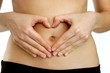 Woman hands forming a heart symbol on belly, isolated