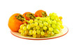 Grapes and persimmons on plate. Isolated on white