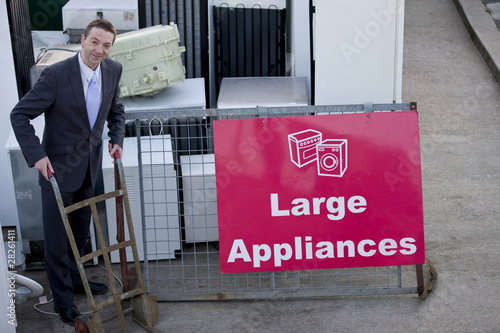 Photo: A businessman standing with a trolley in a recycling center A businessman standing with a trolley in a recycling center