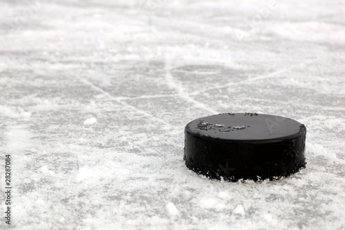Photo: black hockey puck on ice rink black hockey puck on ice rink