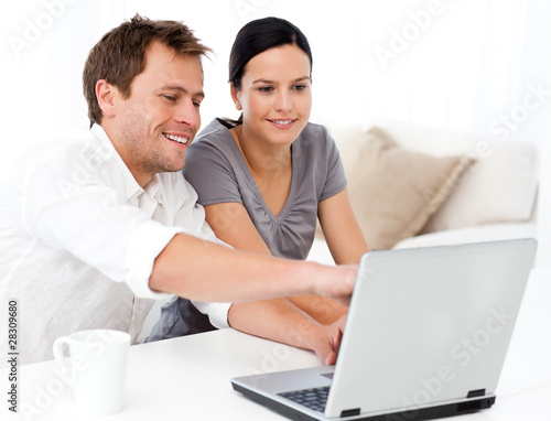 Photo: Cute man showing something on the laptop screen to his wife Cute man showing something on the laptop screen to his wife