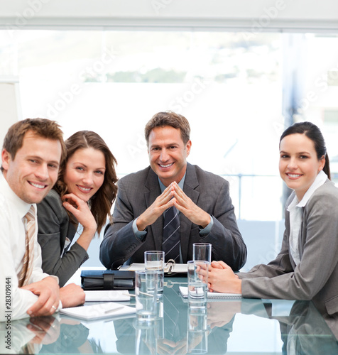 Photo: Portrait of a positive manager with his team sitting at a table Portrait of a positive manager with his team sitting at a table