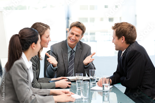 Photo: Delighted managertalking to his team at a table Delighted managertalking to his team at a table