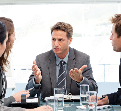 Photo: Severe manager talking to his team at a table Severe manager talking to his team at a table