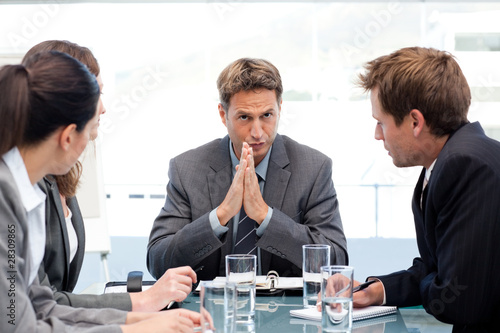 Photo: Serious manager talking to his team during a meeting Serious manager talking to his team during a meeting