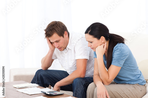 Photo: Worried couple looking at their bills on the sofa Worried couple looking at their bills on the sofa