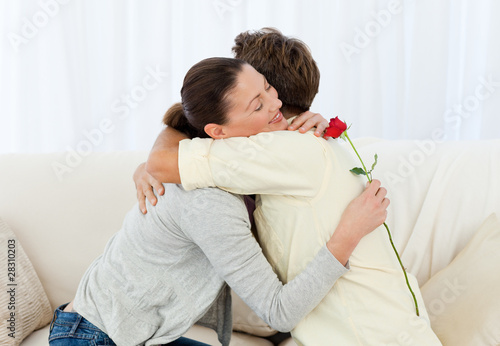 Foto: Lovely woman hugging his boyfriend after receiving a flower Lovely woman hugging his boyfriend after receiving a flower