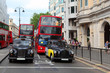 Red double-deckers with tourists and taxi on street of London