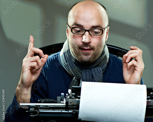 Photo: Old fashioned bald writer in glasses writing book Old fashioned bald writer in glasses writing book