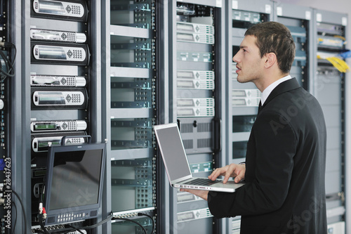 Photo: businessman with laptop in network server room businessman with laptop in network server room