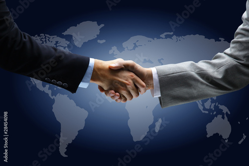 Foto: Handshake with map of the world in background Handshake with map of the world in background