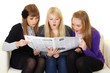 Three young girls reading newspaper Three young girls reading newspaper