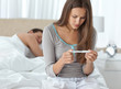 Photo: Pretty woman looking a pregnancy test while her boyfriend sleepi Pretty woman looking a pregnancy test while her boyfriend sleepi