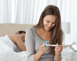 Photo: Happy woman looking a pregnancy test while her boyfriend sleepin Happy woman looking a pregnancy test while her boyfriend sleepin