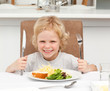 Excited boy holding forks to eat pasta and salad